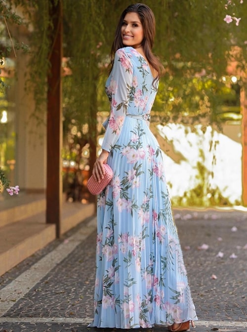 madrinha de casamento ao ar livre usando vestido de festa longo azul claro com mangas longas e estampa de flores cor de rosa 